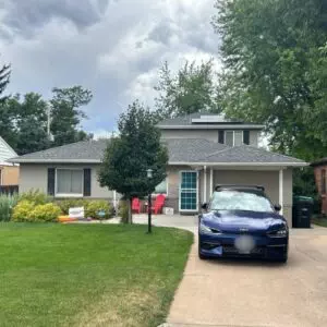 Home with a gray roof that had a solar roof installation, a blue car parked in the driveway in Denver, CO 