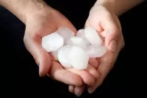 Hands holding hail after Denver hail storm.