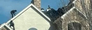 Roofers work on a steeply pitched residential roof during replacement, highlighting how roof pitch impacts roof replacement cost. Denver experts at Elite Roofing & Solar demonstrate safety and precision on complex roof structures.